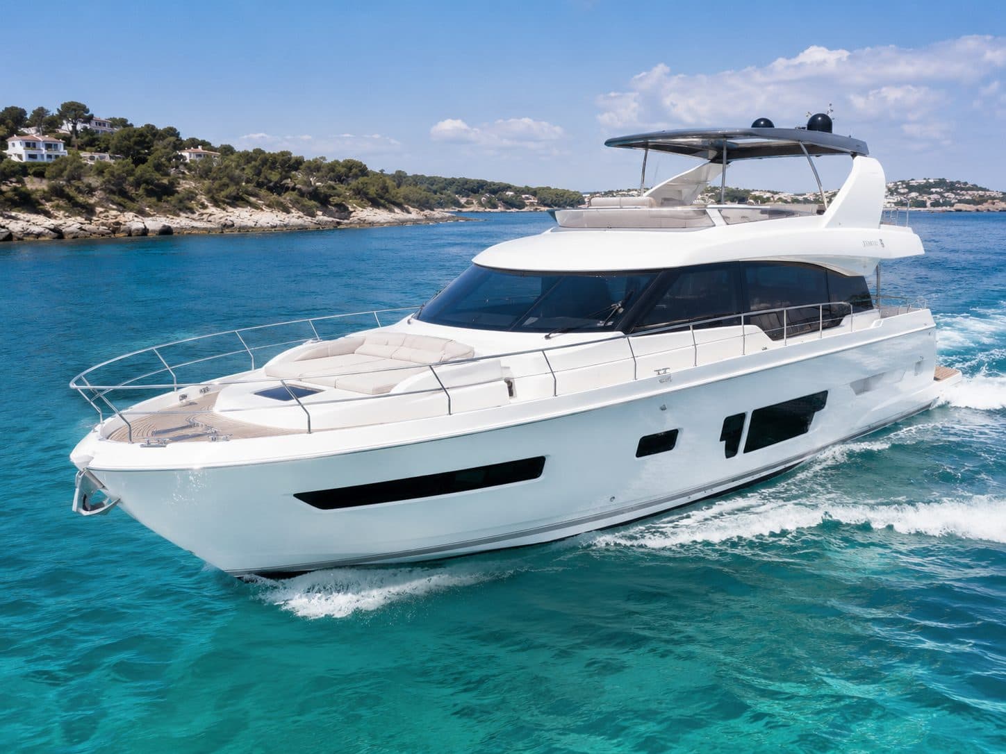 A luxury motor yacht cruising past a coastline